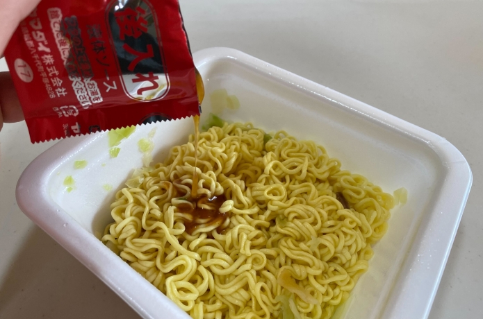 仙台牛タン風味塩焼きそばにソースをかけているようす